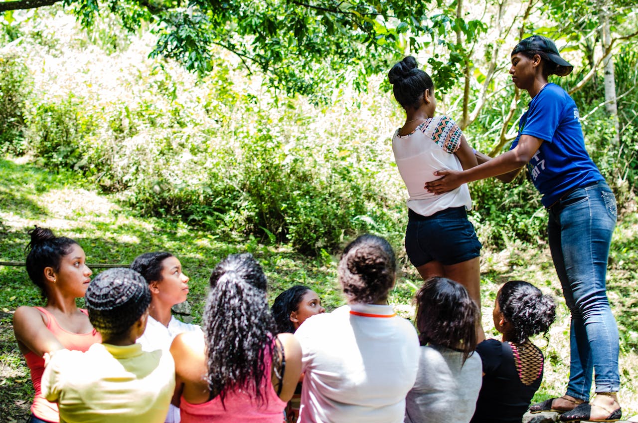 about-01 Diverse group participating in an outdoor team building exercise in a lush green setting.