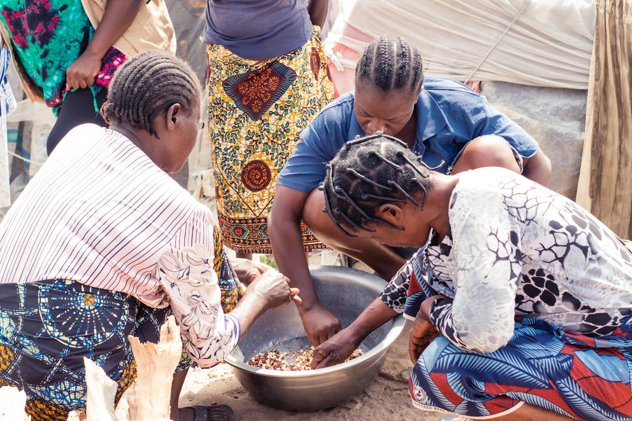 gallery-1 Group of women collaboratively sorting beans outdoors, showcasing cultural richness.