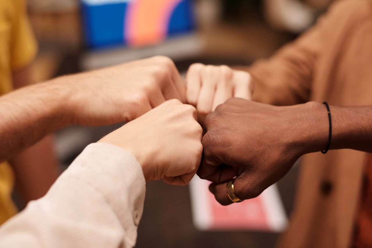services-01 Close-up of a diverse group doing a fist bump, symbolizing teamwork and unity.